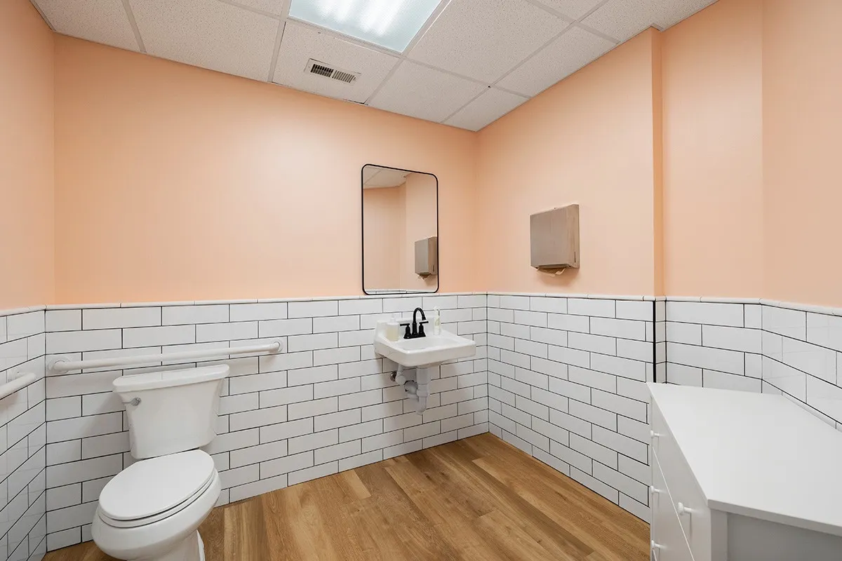 A clean restroom with peach walls and white subway tiles.