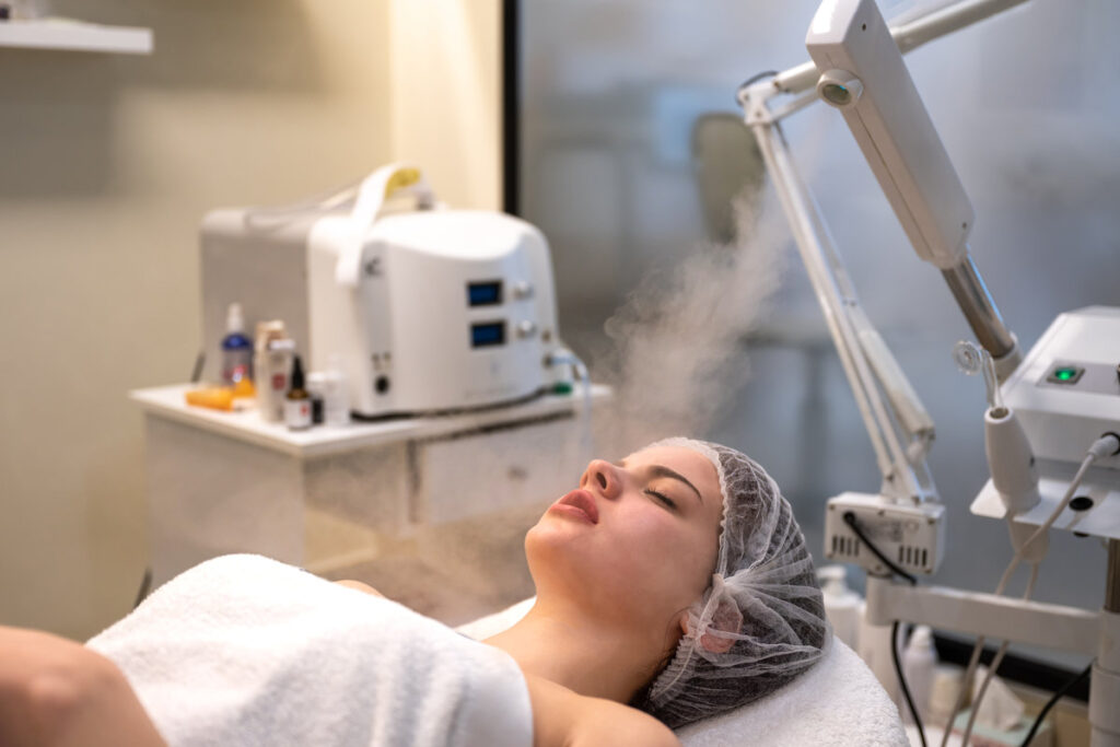 Beautiful woman on ozone therapy with facial steamer in beauty salon.