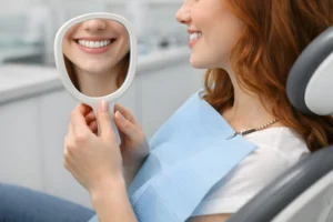 Smiling woman admiring her teeth in a handheld mirror